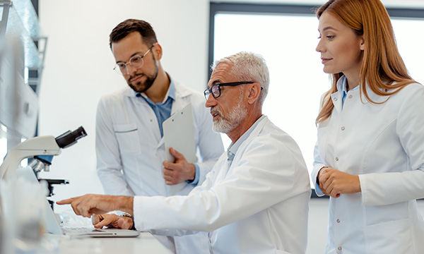 Three healthcare workers in white coats looking at lab results